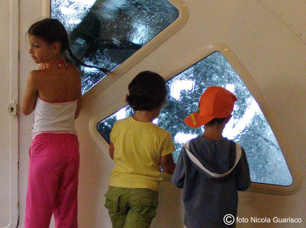 bambini guardano le ruote a pale dalle vetrate interne del piroscafo concordia lago di como in navigazione, battello nave a vapore