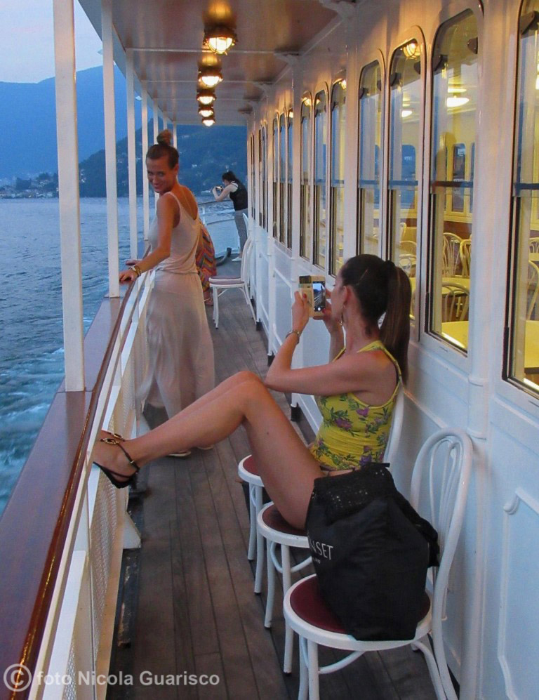 modelle e gambe sul ponte di poppa lungo la ringhiera a bordo del piroscafo concordia lago di como in navigazione, battello nave a vapore