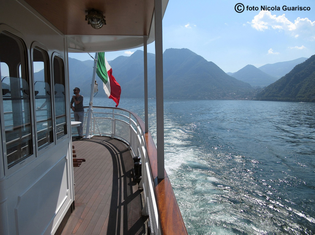 ponte di poppa con bandiera italiana tricolore e la scia del piroscafo concordia lago di como in navigazione, battello nave a vapore