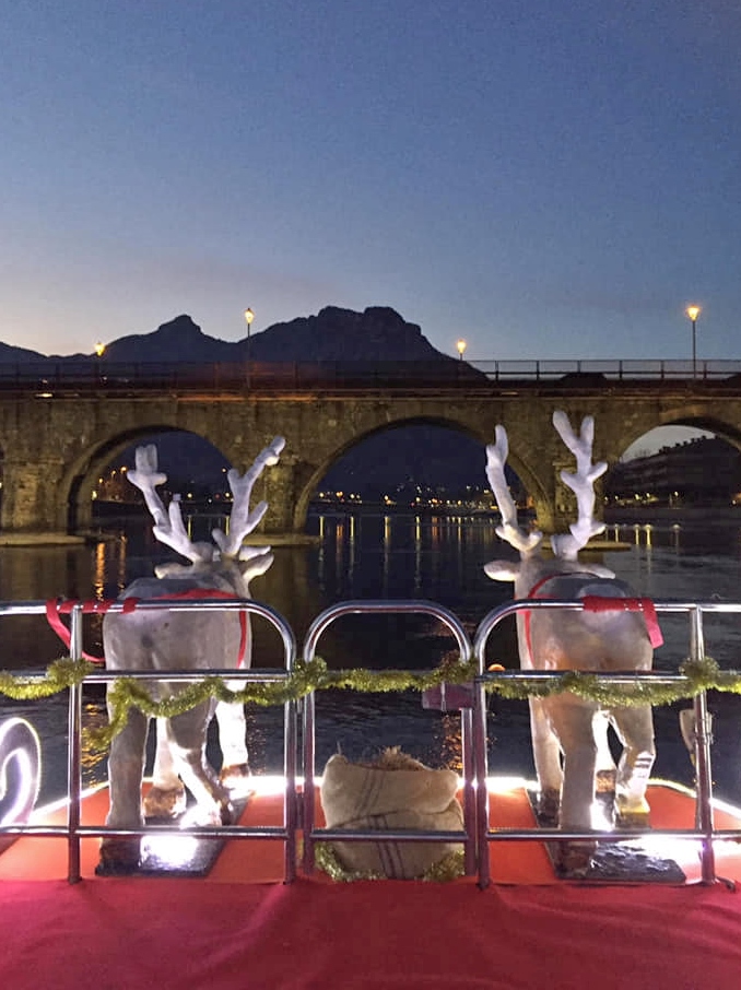 renne trainano la slitta galleggiante di babbo natale a lecco con lo sfondo del ponte azzone visconti, foto ingrid anghileri