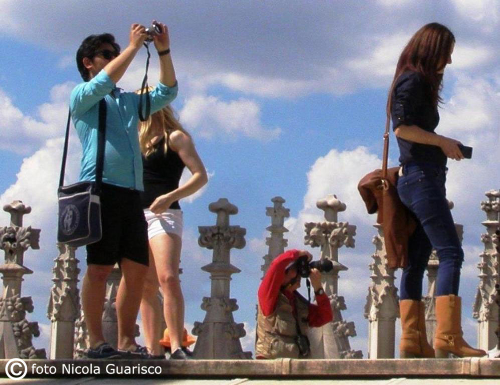 turisti sulle terrazze del duomo di milano con le guglie