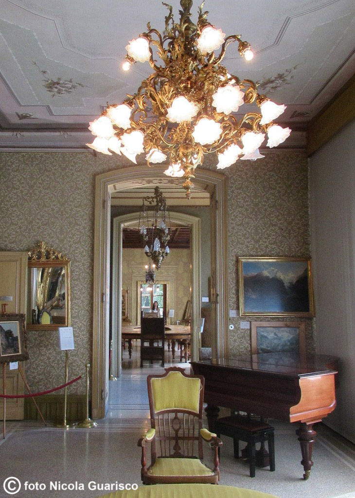 lago di como villa monastero varenna, pianoforte,lampadario e corridoio elegante nei saloni della villa