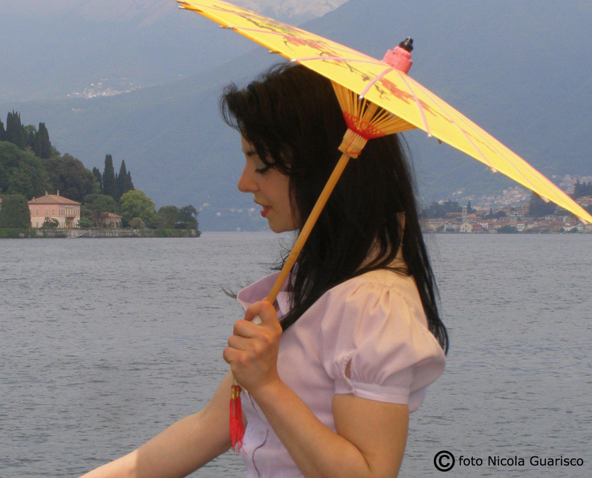 ragazza turista cinese con ombrellino o ombrello parasole con lo sfondo di villa pizzo a cernobbio sul lago di como