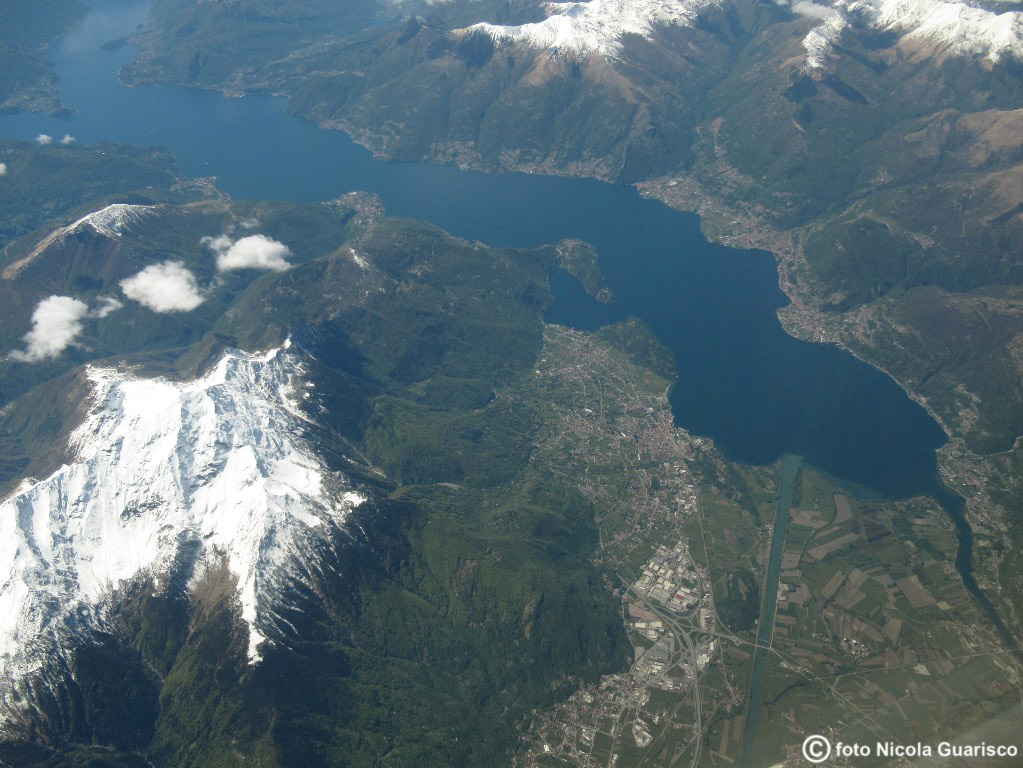 alto lago di como visto dall'aereo, foto aerea.L'intera regione settentrionale del lago, volando sopra la cima innevata del monte Legnone. A destra: il Pian di Spagna e i fiumi immissari. In alto a sinistra: Bellagio e l'isola Comacina